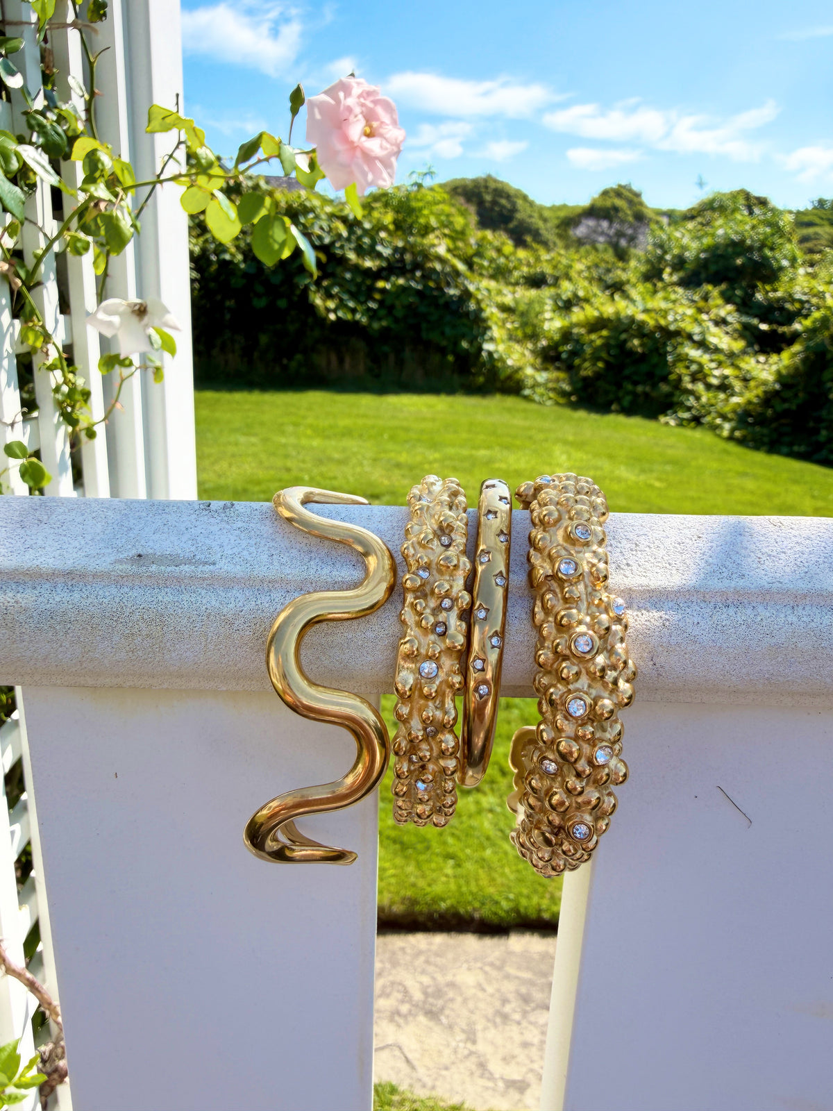Assorted gold cuff bracelets on a porch railing