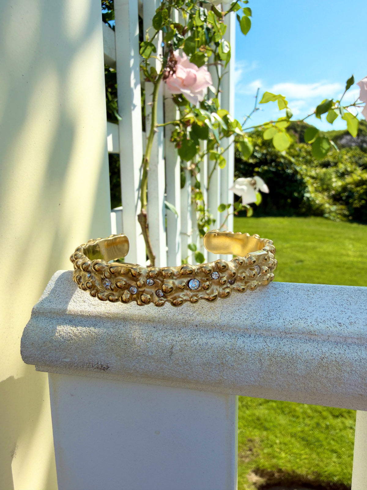 Textured gold cuff on a sunlit porch railing