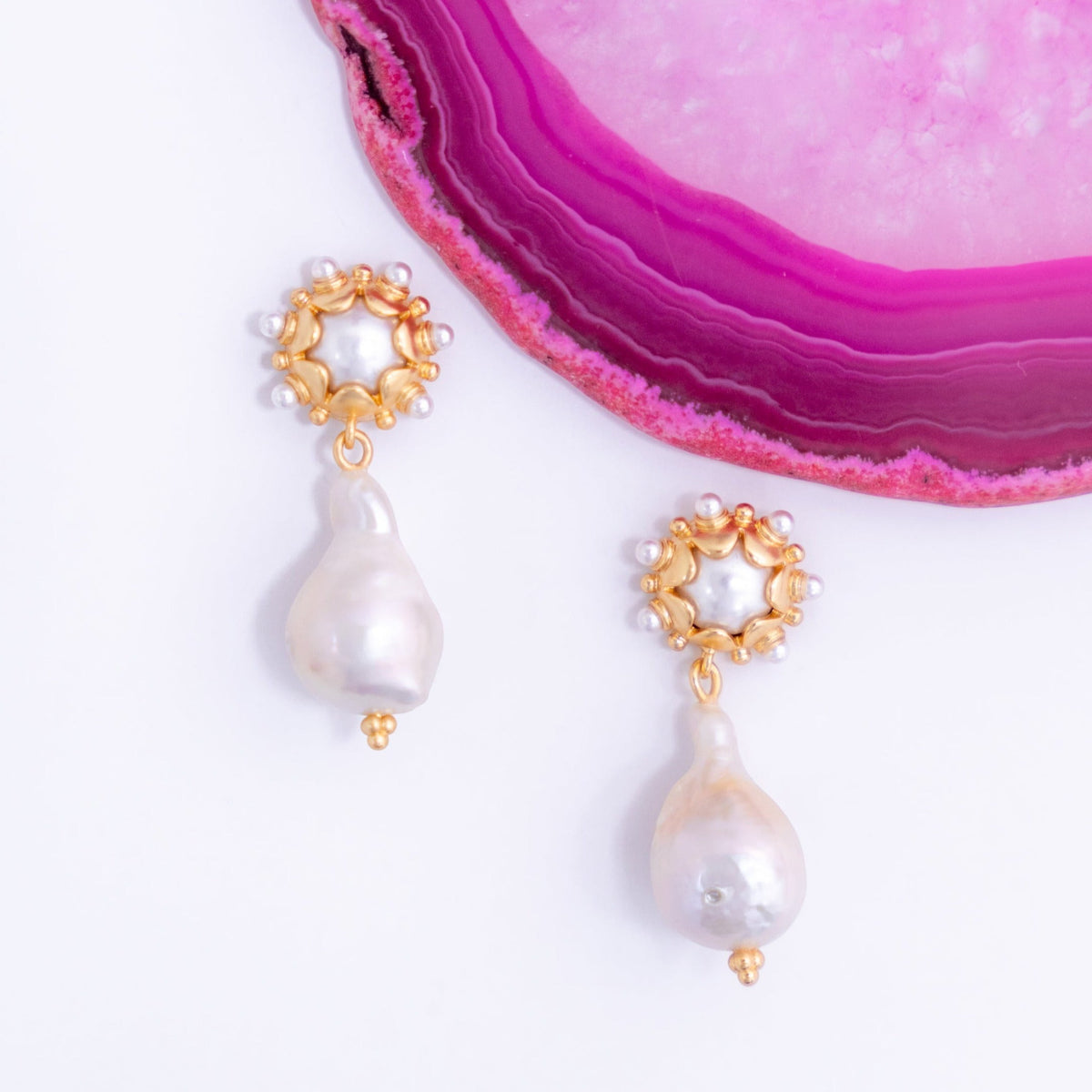 Small Clio pearl drop earrings on a pink agate slice
