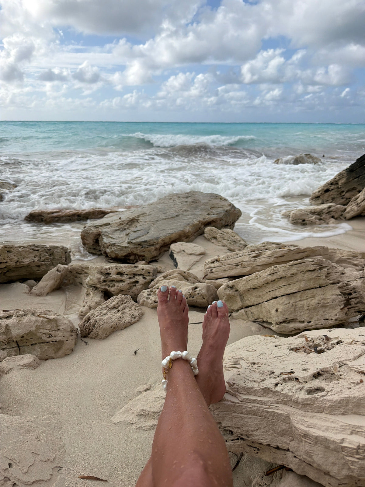 Pearl anklet worn at the beach beside ocean rocks