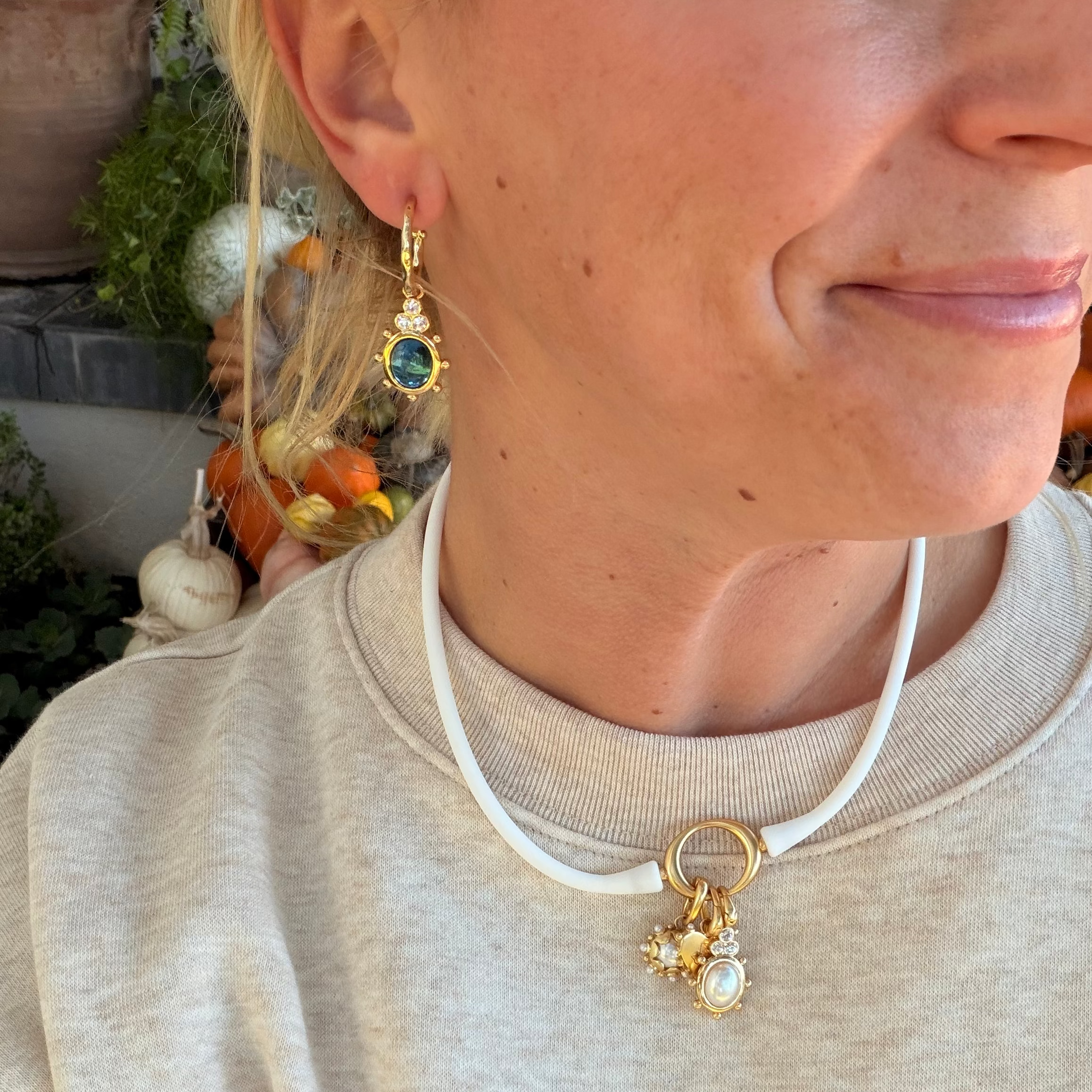 Woman wearing a white Ellipse silicone necklace with a gold oval centerpiece