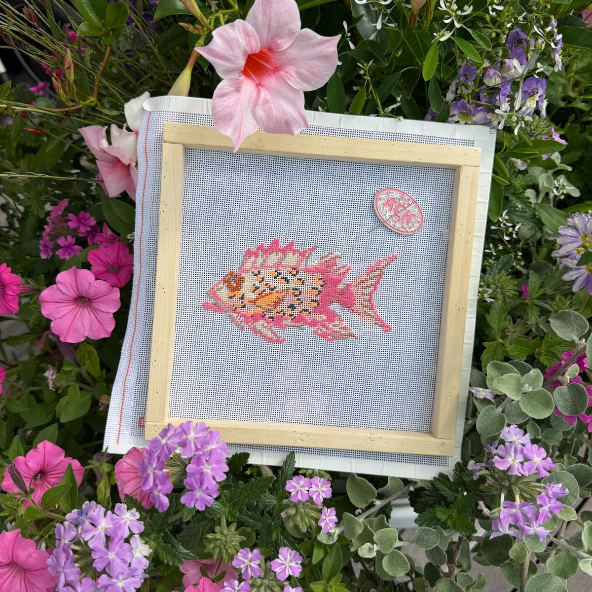 ACK needle minder attached to a framed needlepoint canvas