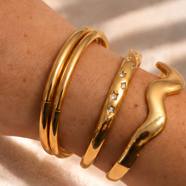 Wrist wearing gold colored bangles and cuffs
