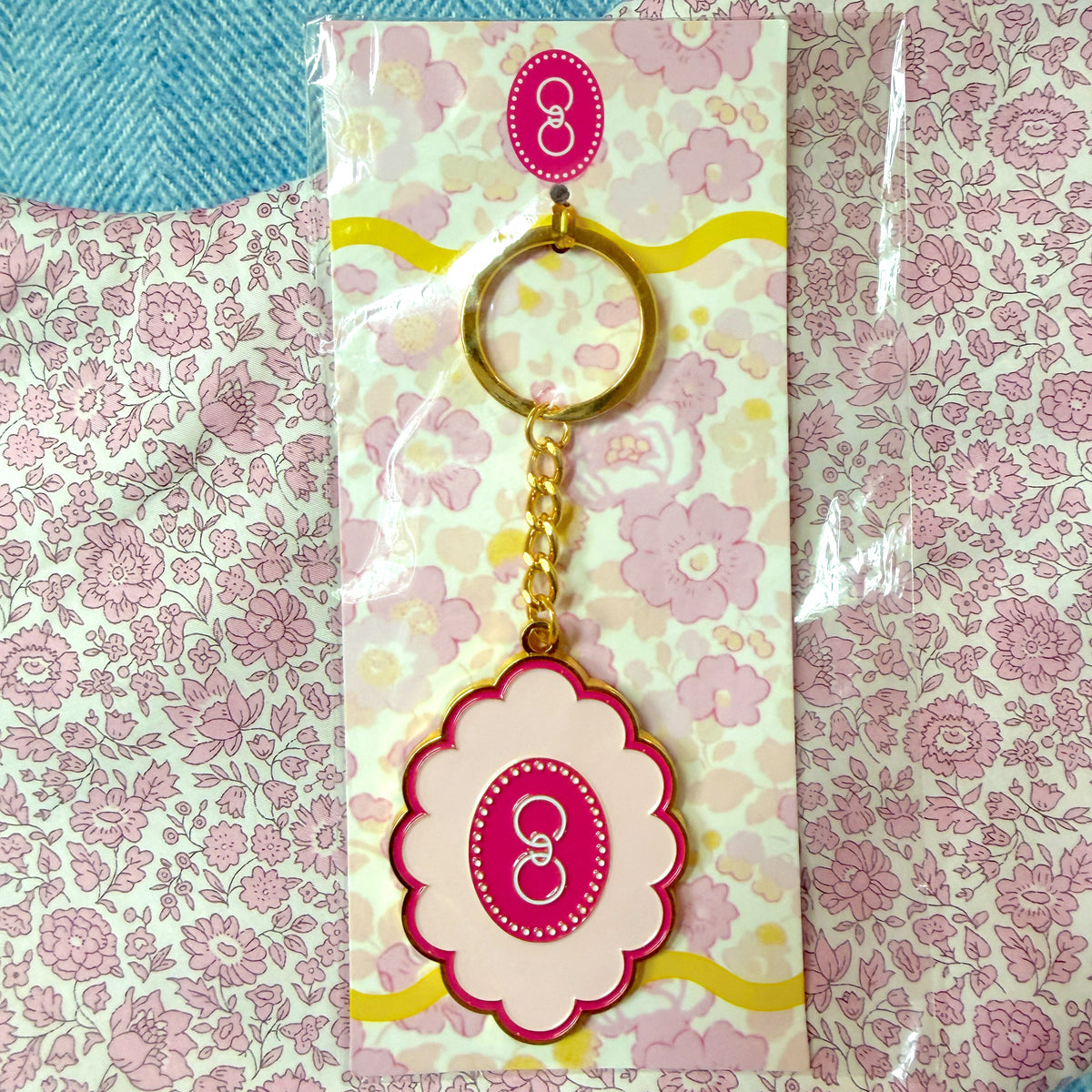 Scallop Gresham logo keychain on a floral background