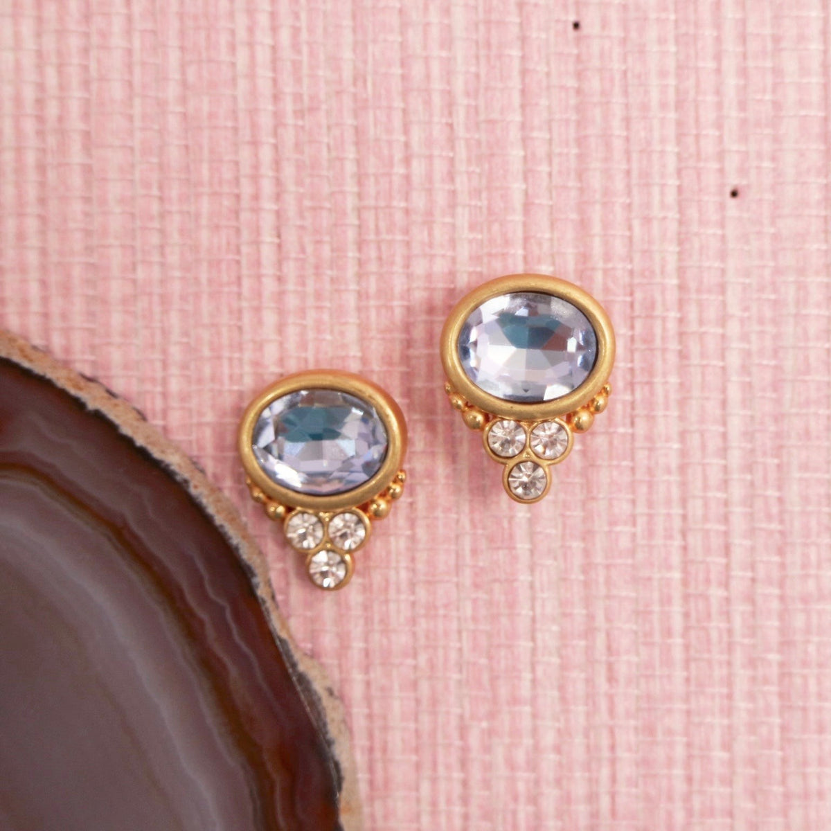 Aquamarine colored BonBon studs beside a dark agate slice