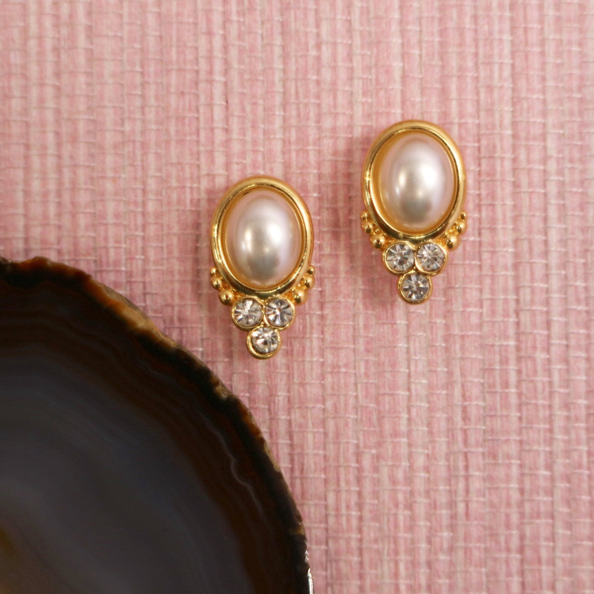 Pearl BonBon studs beside a dark agate slice
