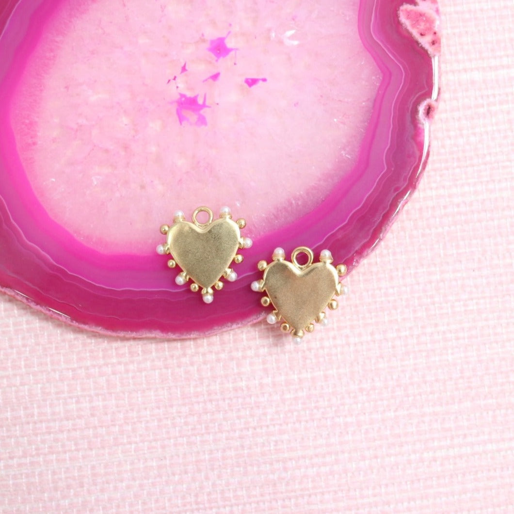 Gold Amore heart earring charms on a pink agate slice