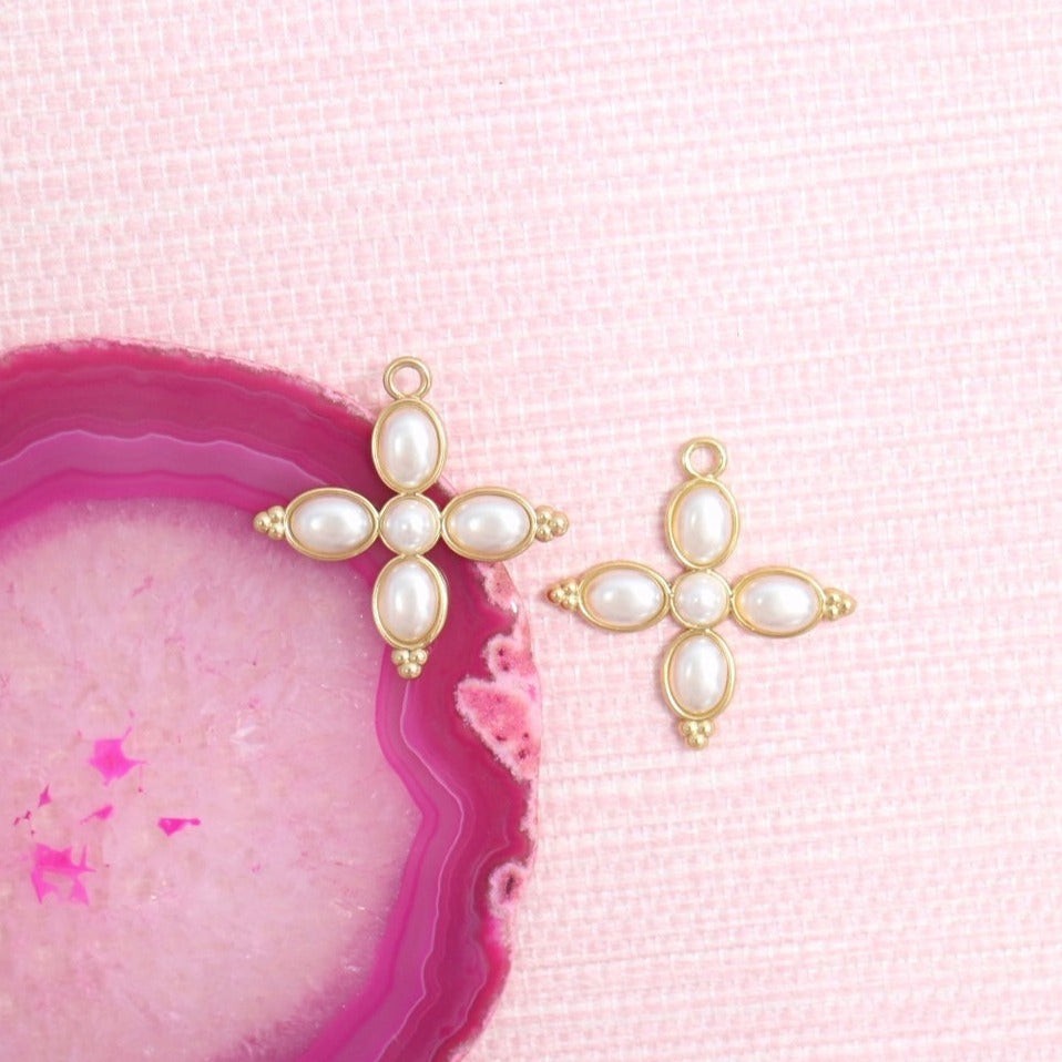 Constance pearl cross earring charm pair on a pink agate slice