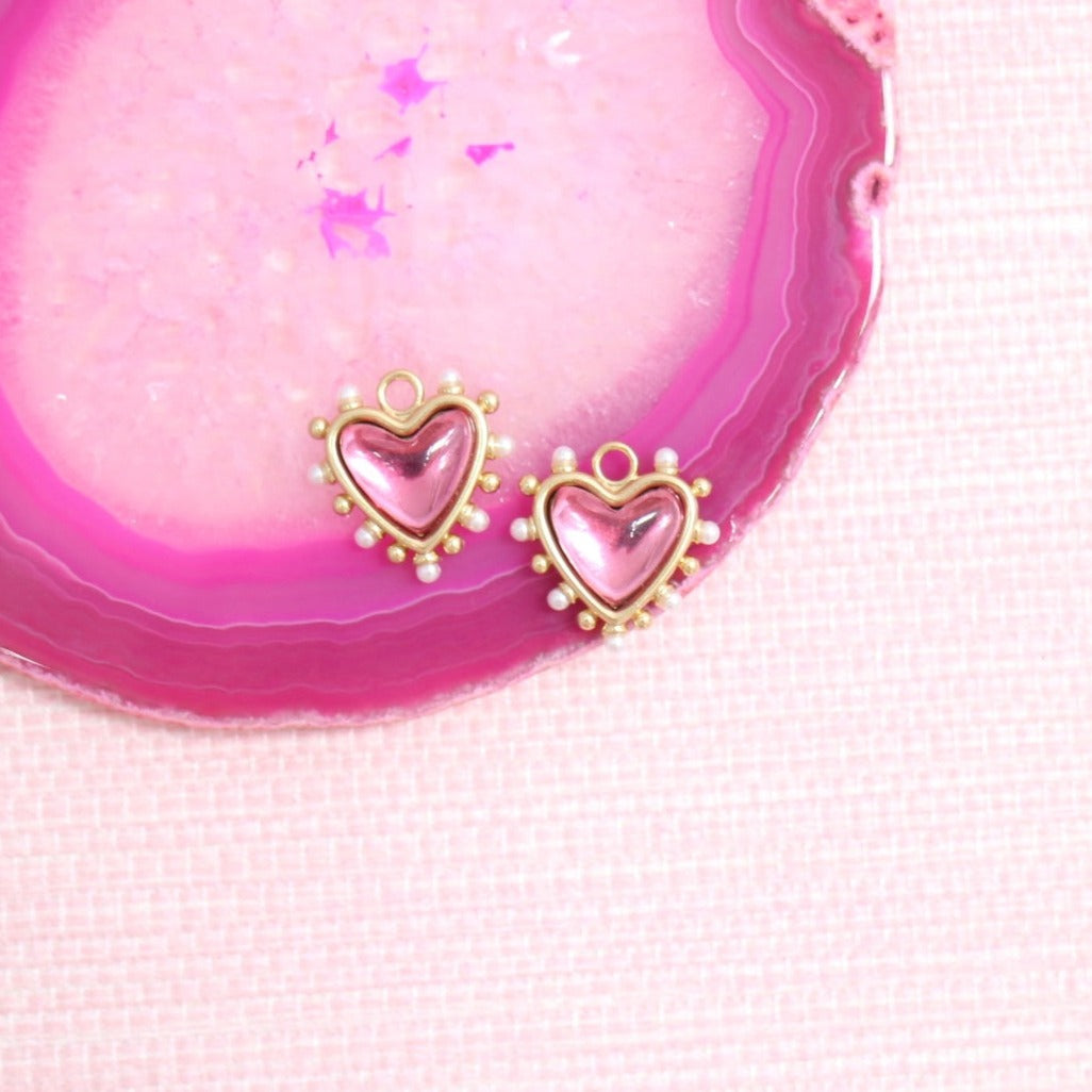 Pink Amore heart earring charms on a pink agate slice