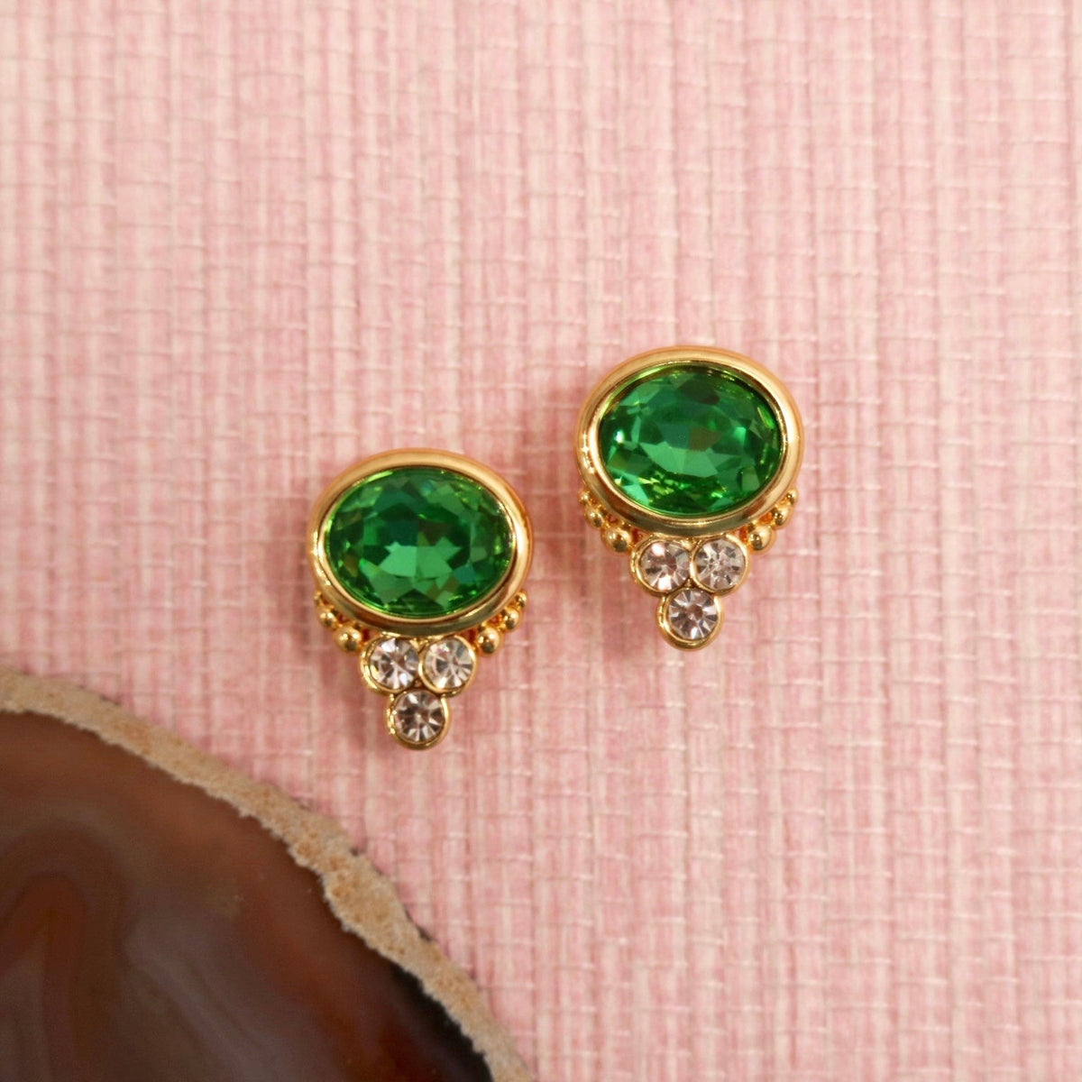 Emerald colored BonBon studs arranged on a pink background