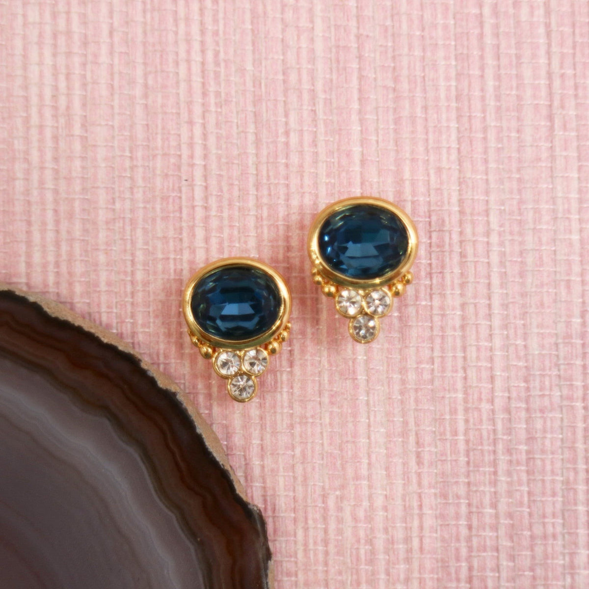 Sapphire colored BonBon studs arranged on a pink background