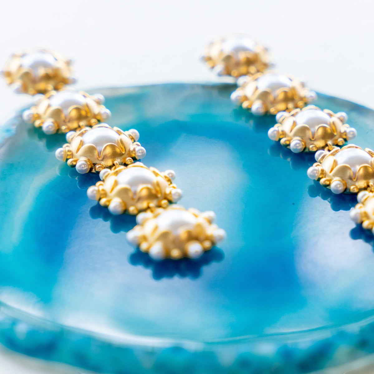 Close-up of pearl and gold details on Perla drop earrings