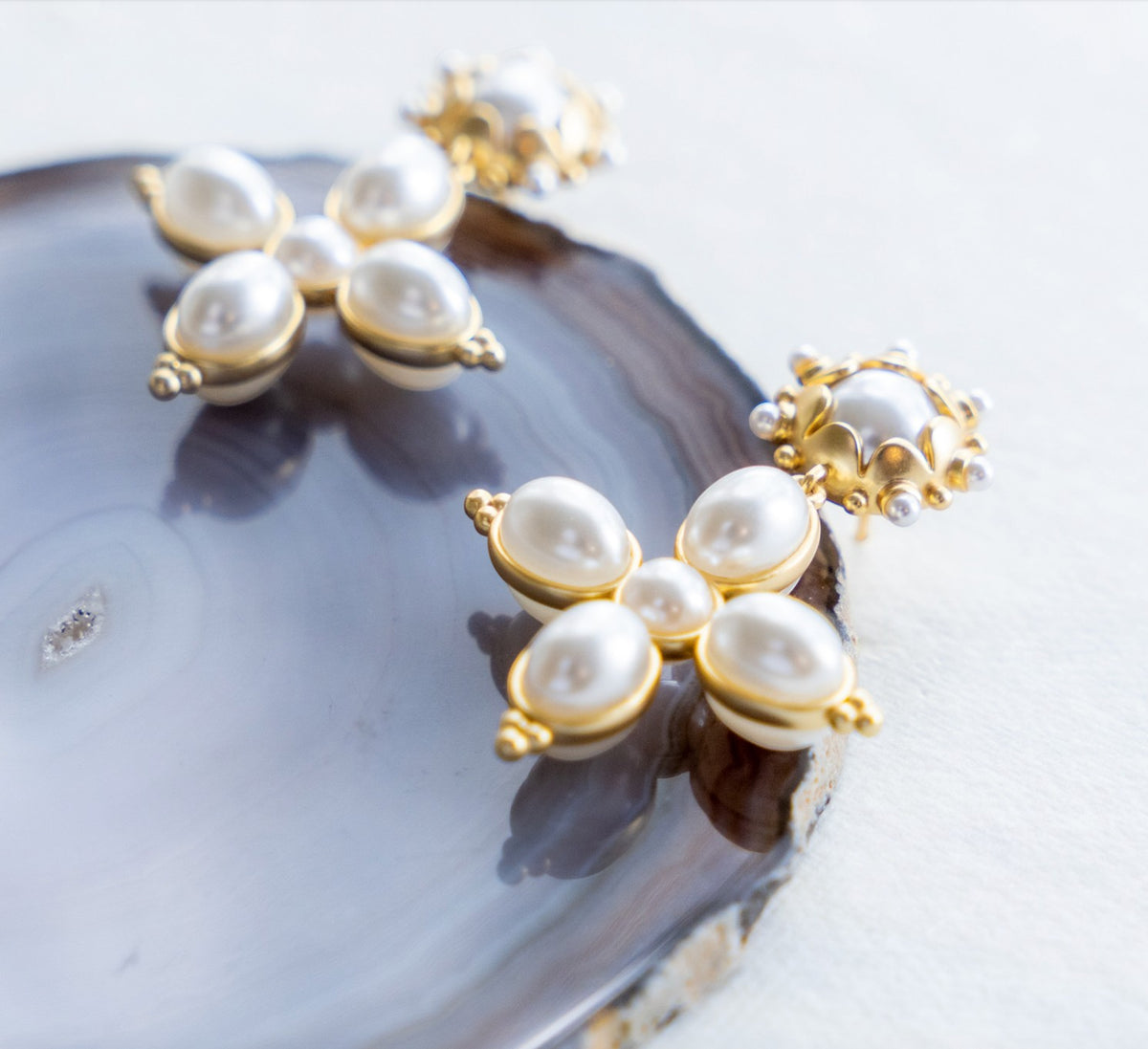 Close-up of pearl cross earrings with gold settings