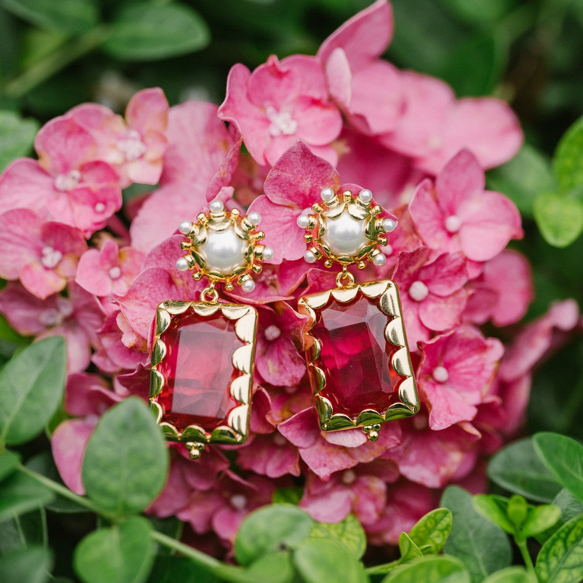 Azalea pink Mini Gemma earrings arranged on pink hydrangeas