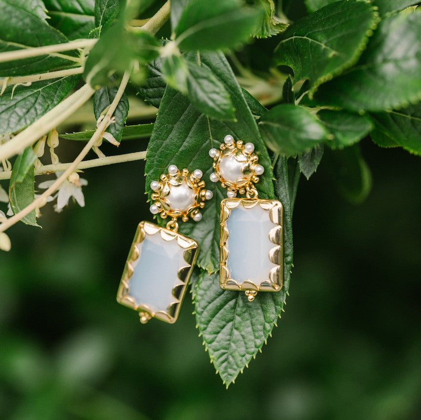 Opal Mini Gemma earrings resting on green leaves