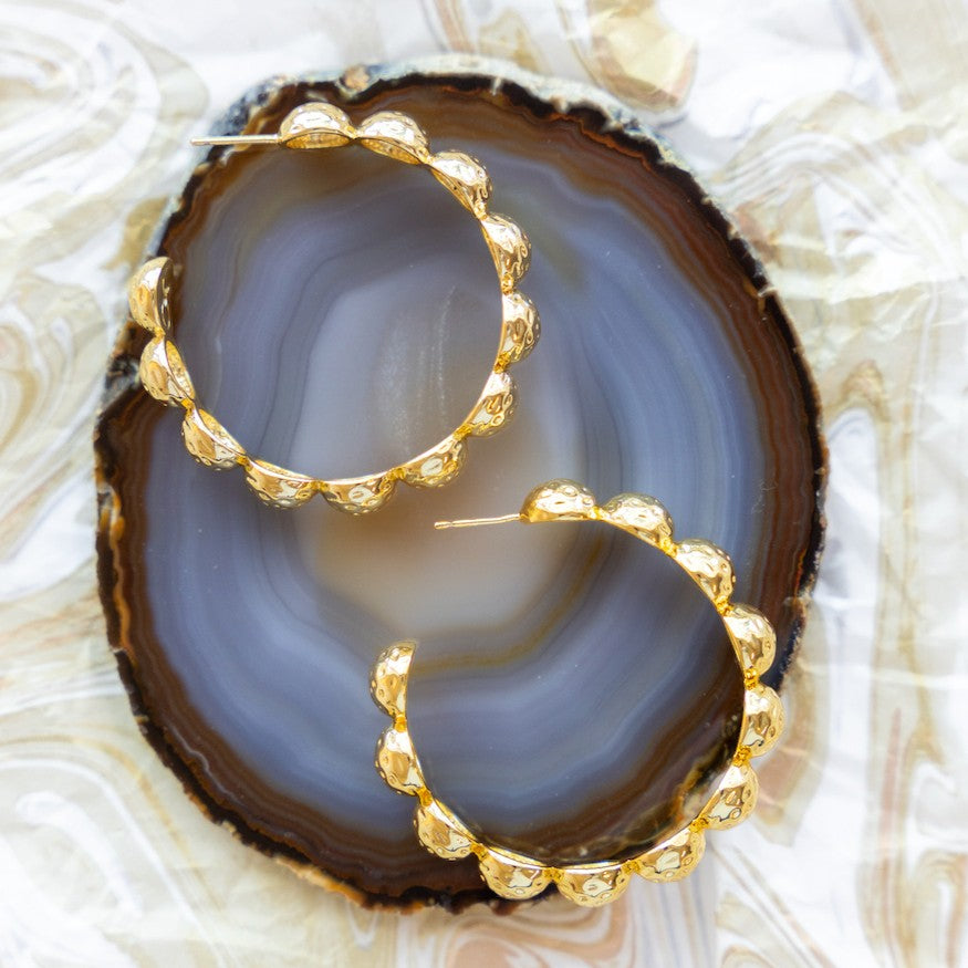 Gold Florence hoop earrings arranged on a dark agate slice