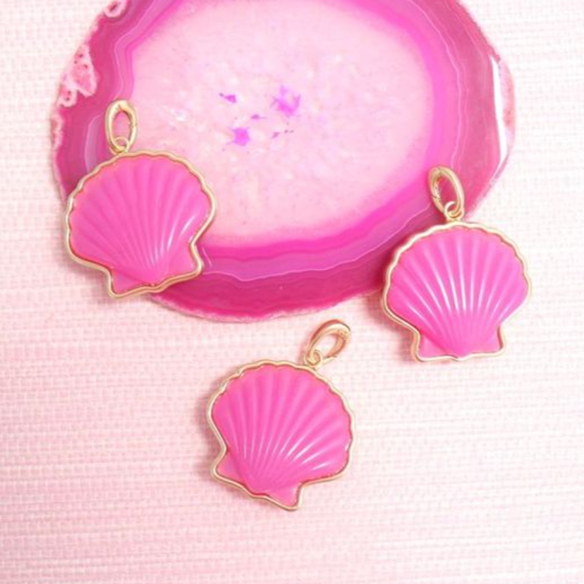 Pink Peregrina shell pendants and charms arranged on pink agate