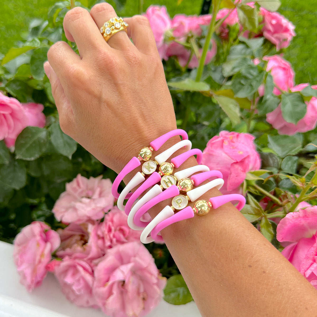 Wrist wearing colorful silicone pearl bracelets beside pink flowers