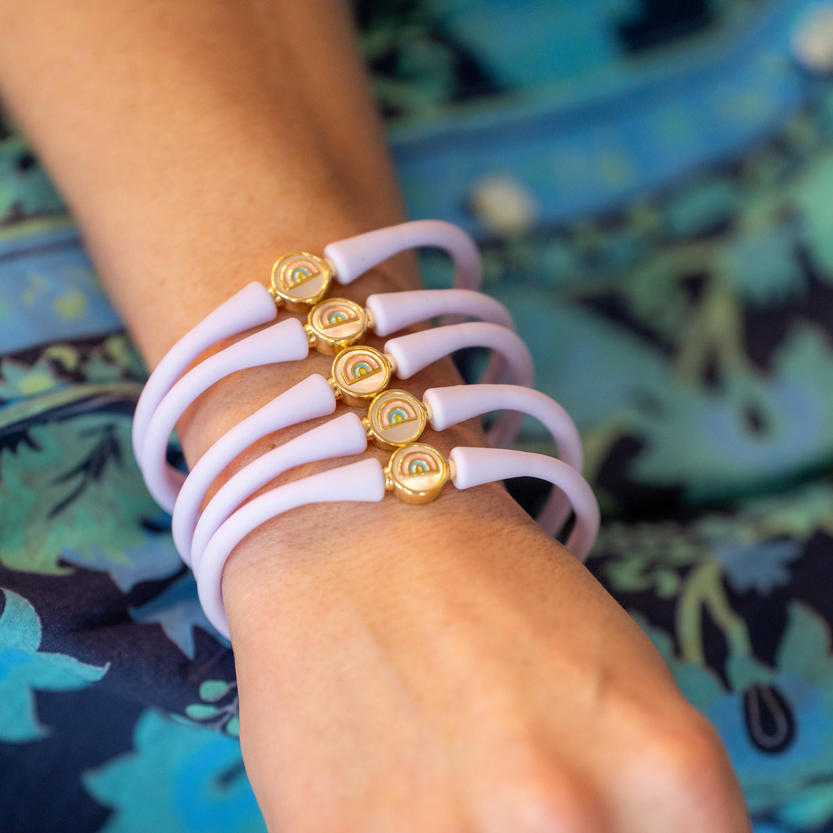 Wrist wearing pastel silicone bracelets with gold ball centerpieces