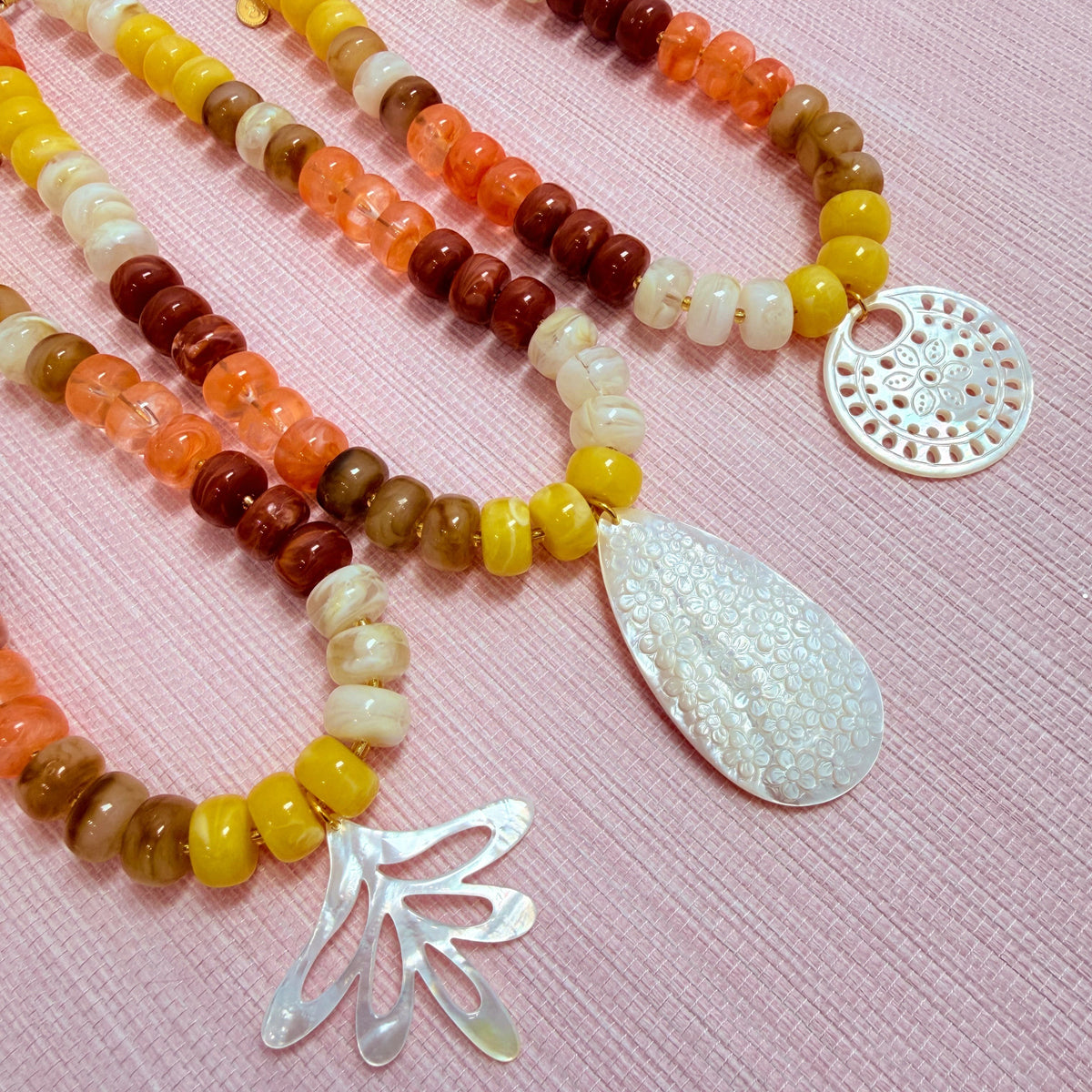 Sunset colored Nardo necklaces with round, teardrop, and fan shaped pendants