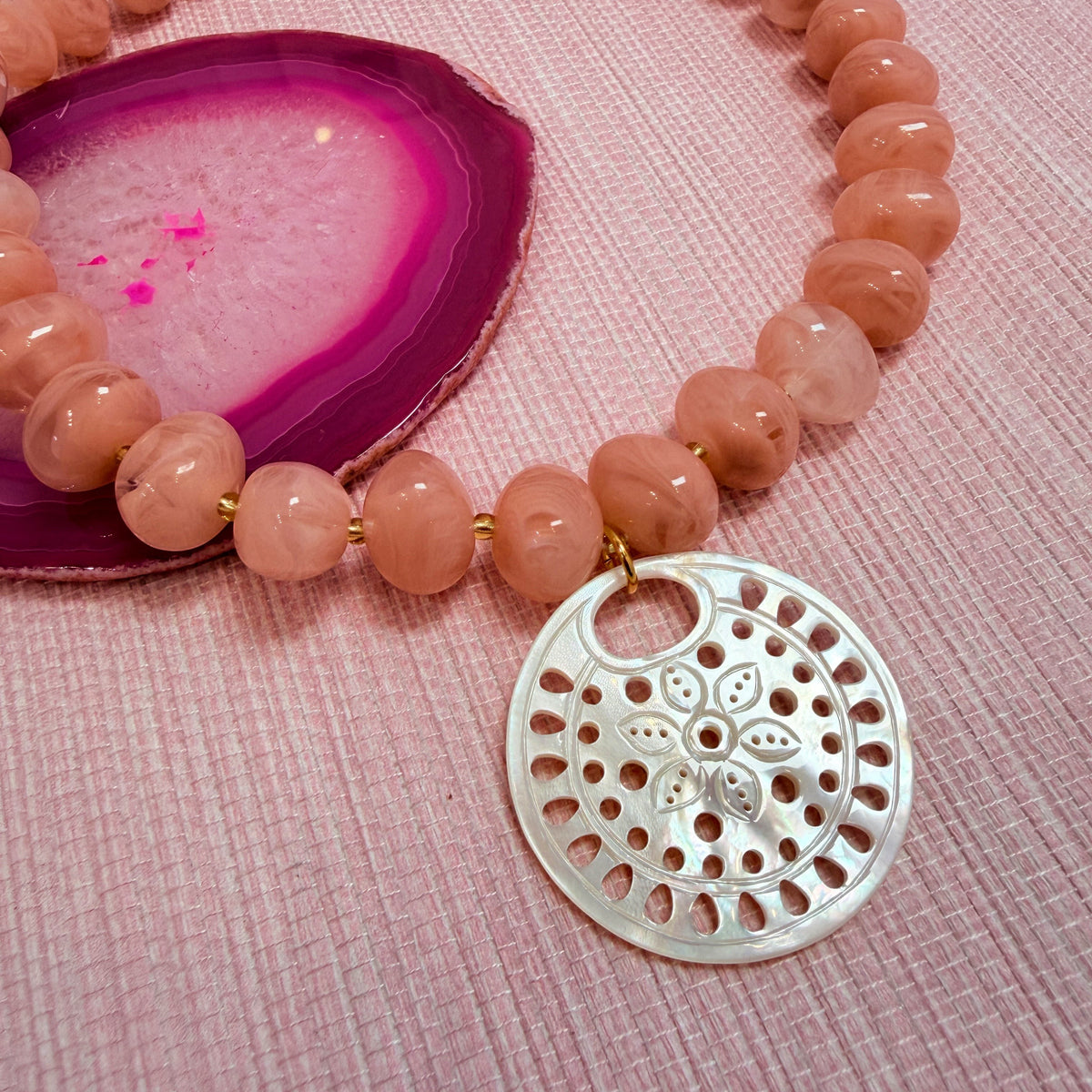 Close-up of a round pendant on the pink Nardo necklace