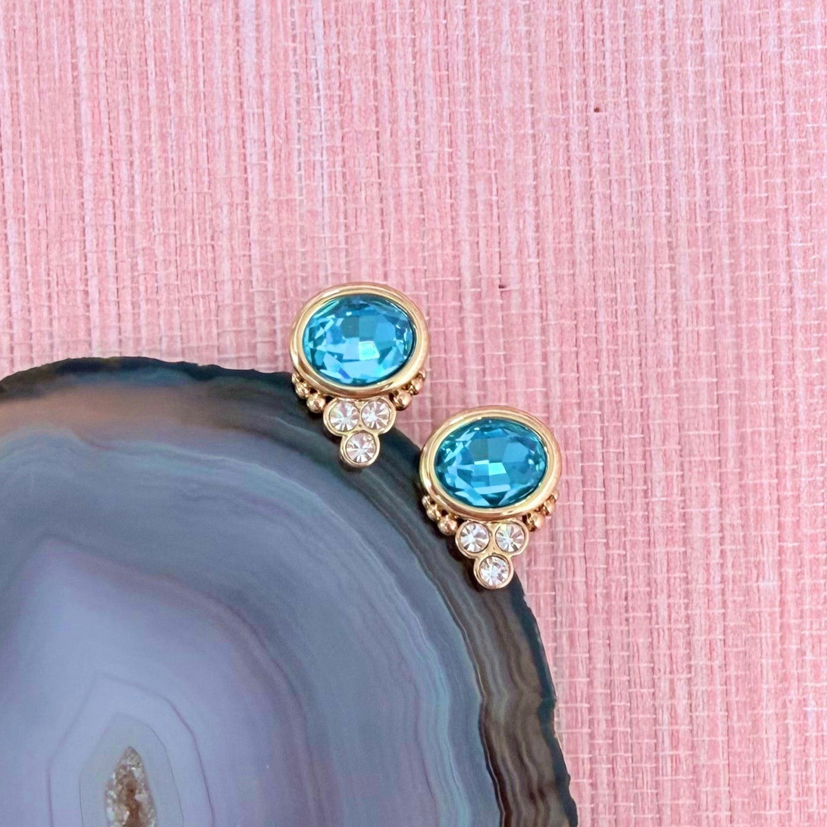 Blue Topaz colored BonBon studs beside a dark agate slice
