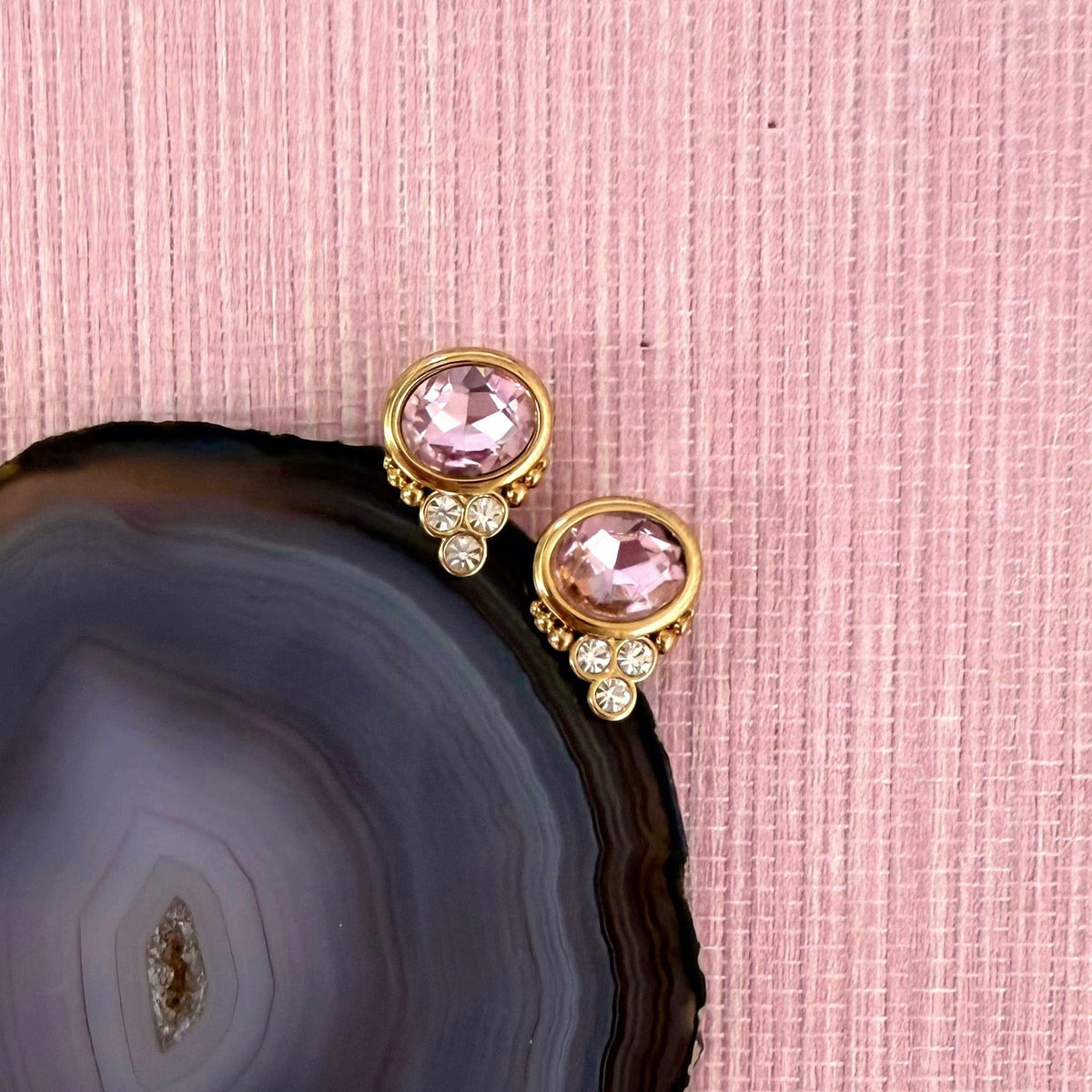 Rose Quartz colored BonBon studs beside a dark agate slice