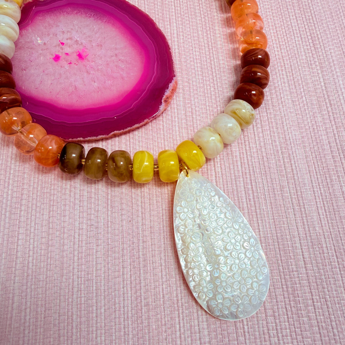 Close-up of sunset colored Nardo beads and a teardrop pendant