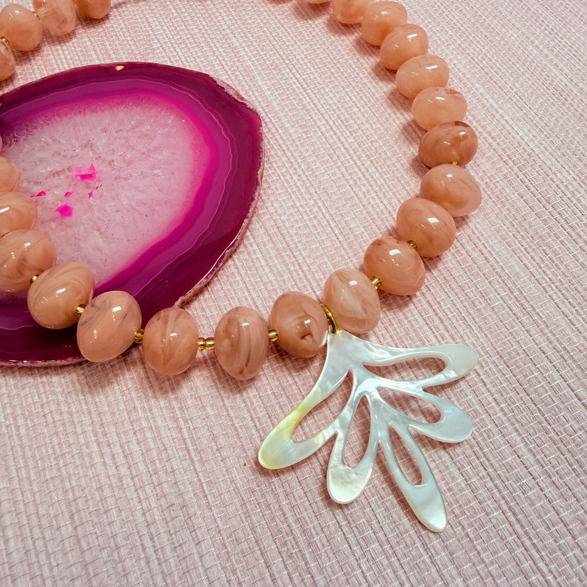 Close-up of a fan shaped pendant on the pink Nardo necklace