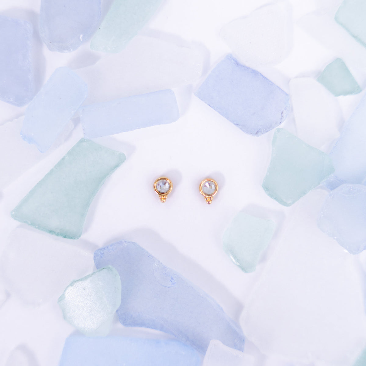 Pair of pale pink Fortuna stud earrings on a pale blue background