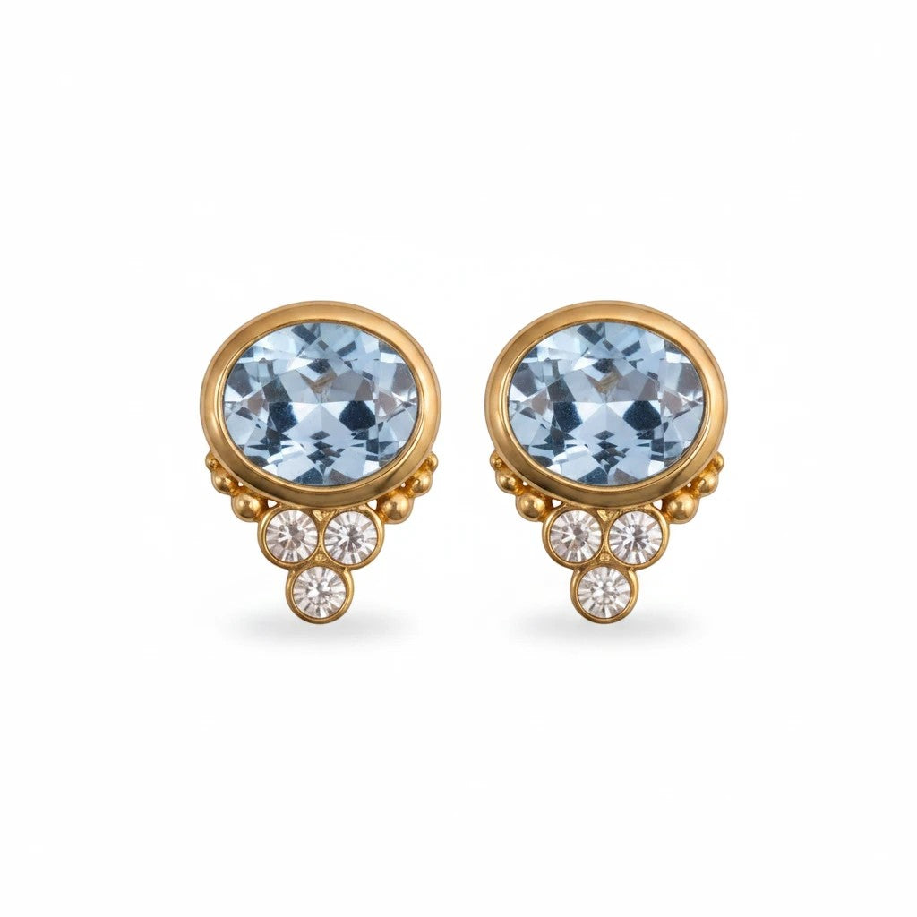 Gresham BonBon aquamarine stud earrings in gold with oval blue stones and small clear accent crystals.