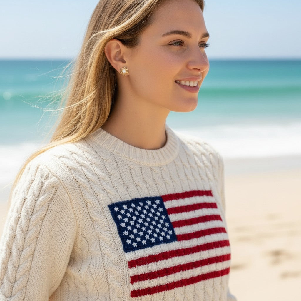 Woman wearing Gresham Perla Studs, 18k gold plated earrings with pearls and scalloped bezel, on a sunny beach.