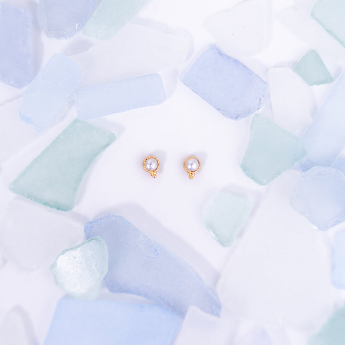 Pair of pink Fortuna stud earrings on a pale blue background