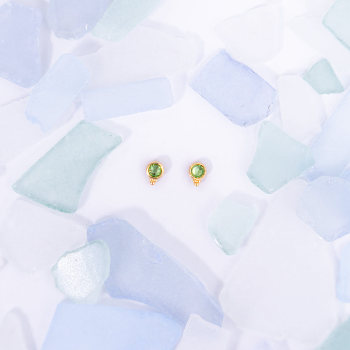 Pair of light green Fortuna stud earrings on a pale blue background