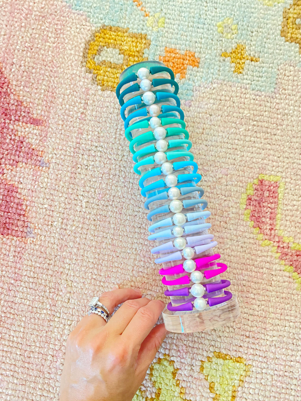 A hand holding a clear tower stacked with colorful silicone bracelets