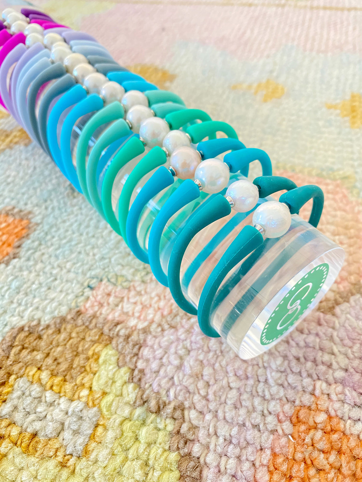 Close-up of silicone bracelets and pearl centerpieces on a clear display tower