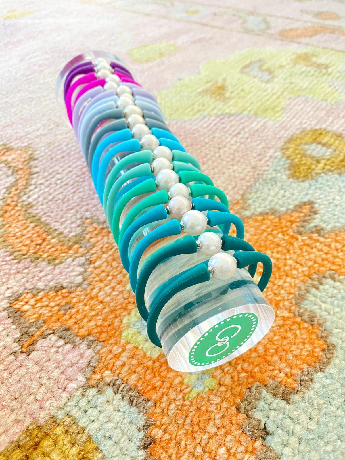 Clear bracelet tower filled with blue and green silicone bracelets
