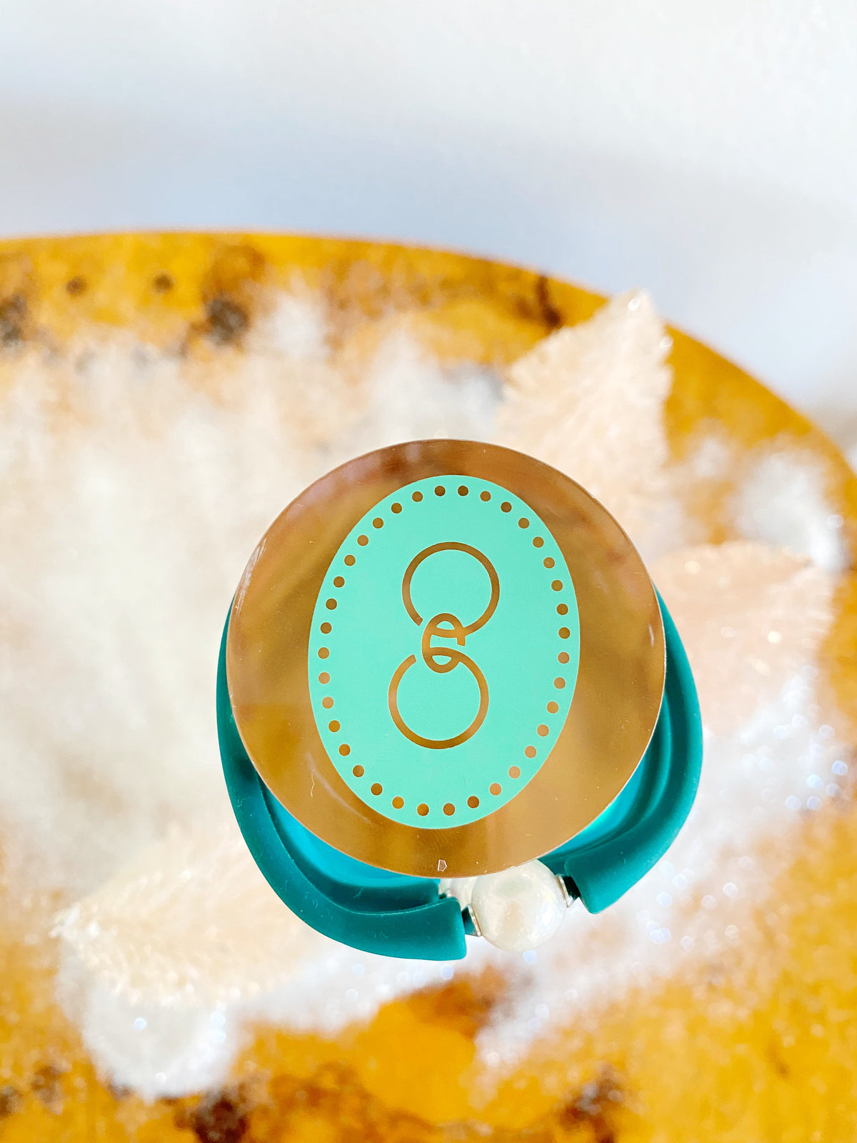 Aqua and gold Gresham logo on a bracelet tower