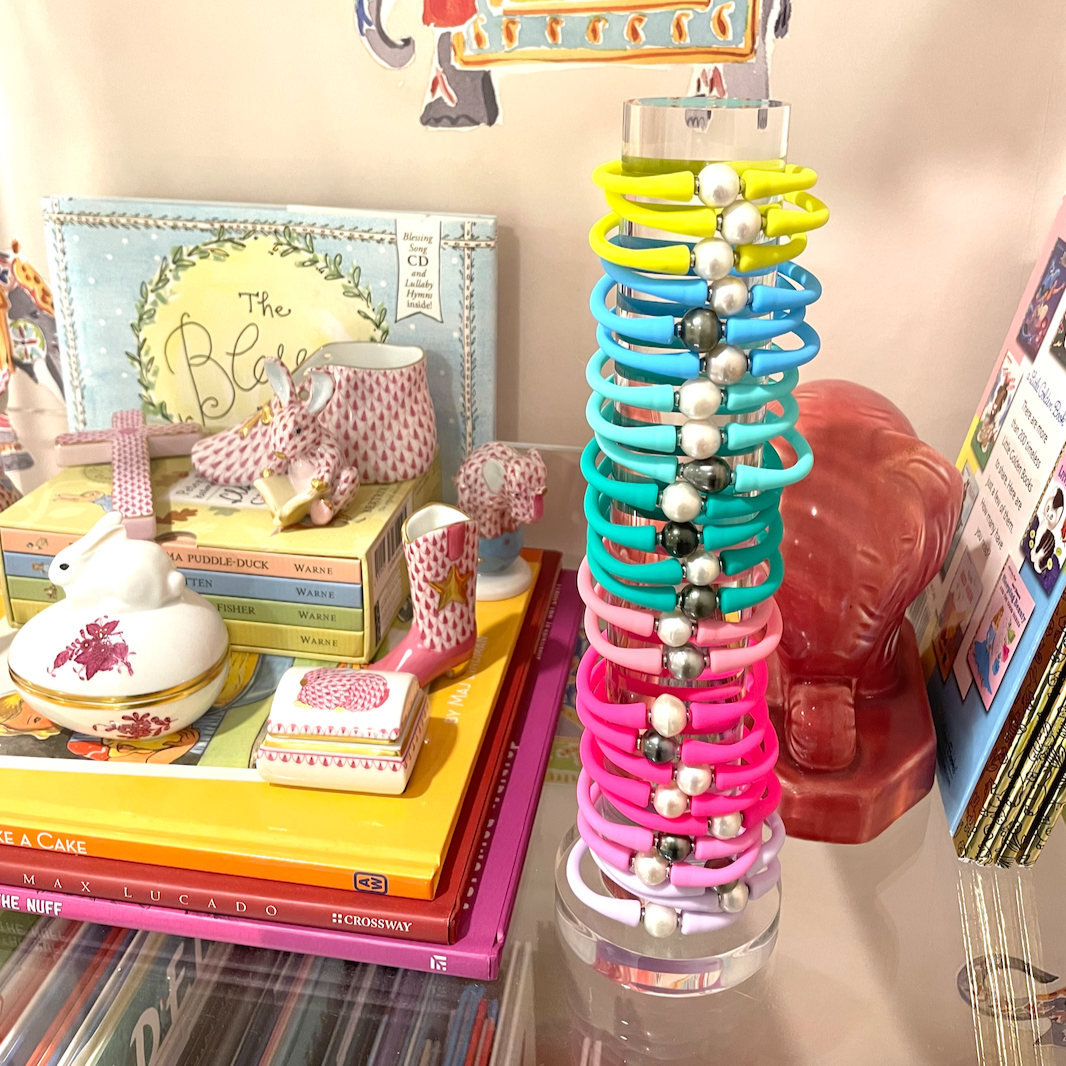 Colorful silicone bracelets stacked on a clear tower among dresser accessories